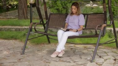 Anne parkta oturan çocuklar için bir kitap okuma