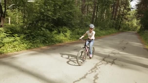 Menina monta sua bicicleta em uma trilha florestal — Vídeo de Stock