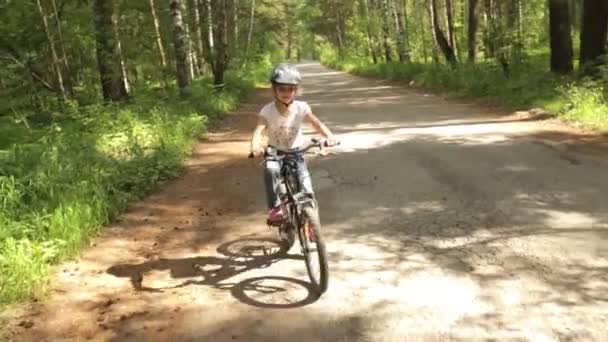 Menina monta sua bicicleta em uma trilha florestal — Vídeo de Stock