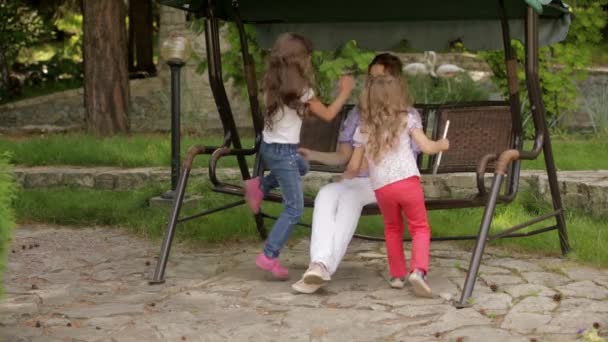 Madre leyendo un libro a los niños sentados en el parque — Vídeo de stock