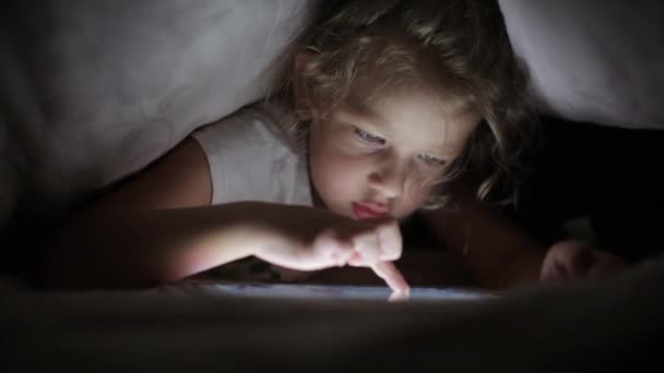 Menina desenho no computador tablet, escondendo-se sob o cobertor — Vídeo de Stock