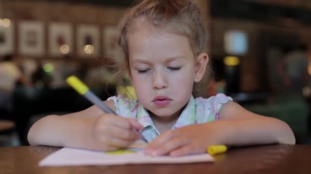 Petite fille dessine dans le café en attendant la commande. enfant au restaurant — Video