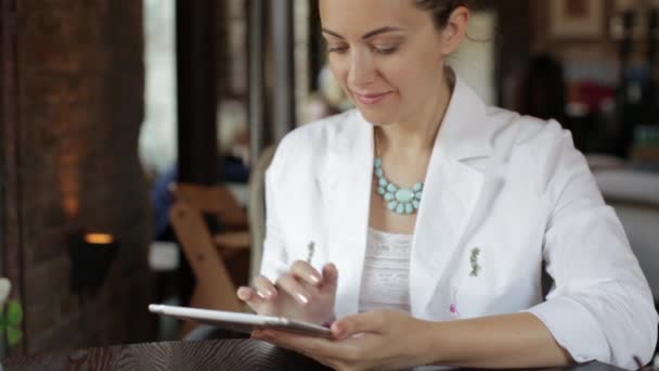 Jonge mooie business lady werken op tablet pc, zitten in een gezellig cafe — Stockvideo