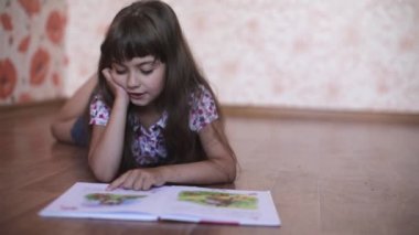 küçük kız yerde yatarken bir kitap okuma