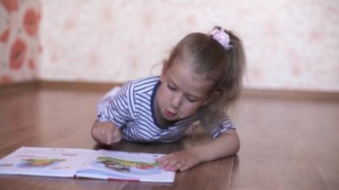 küçük kız yerde yatarken bir kitap okuma