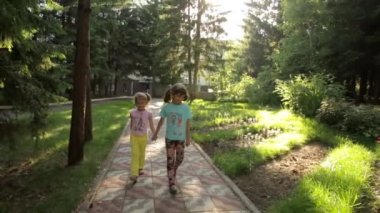 iki küçük kız Park ve tutuşup yürüyerek. çocuklar açık havada zaman harcamak