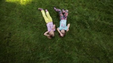 iki küçük kız çim ve konuşma üzerinde yalan. kız arkadaşı birlikte vakit geçirmek. Üstten Görünüm