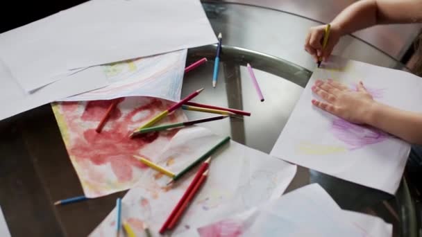 Meisje tekent u met kleurpotloden zittend aan tafel. Close-up — Stockvideo