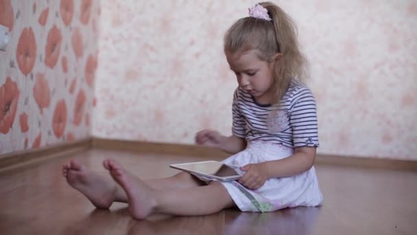 Kleines Mädchen liest ein Buch, während es auf dem Boden liegt — Stockvideo