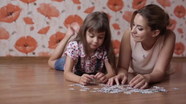 Little girl collects puzzles with mom lying on the floor — Stock Video