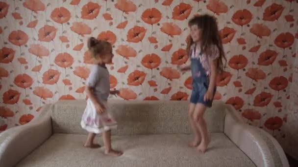 Iki küçük kız oynama ve kanepeye atlama — Stok video
