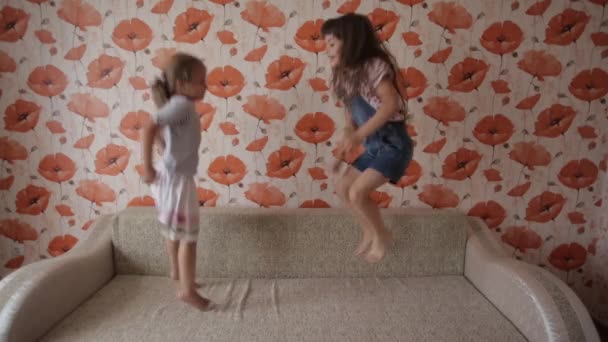 Due bambine che giocano e saltano sul divano — Video Stock