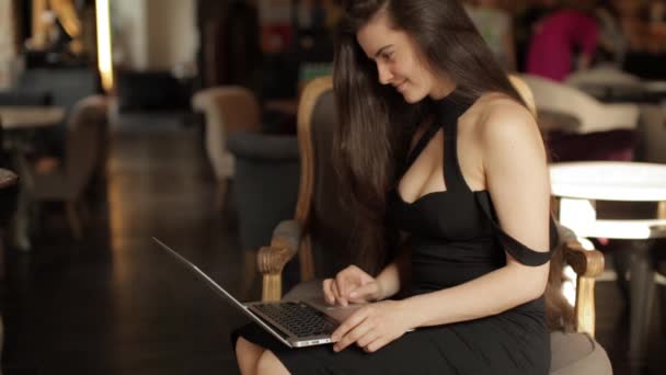 Mooi meisje werkt op laptop in café — Stockvideo