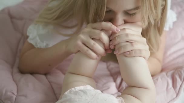 Jonge mooie moeder kust haar babys kleine hakken. Moederlijke liefde voor haar dochter. Baby voeten dicht tot — Stockvideo