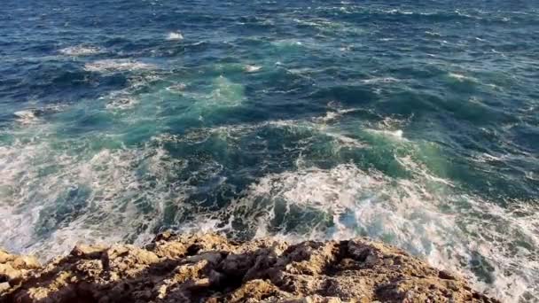 Olas de agua azul y una playa rocosa — Vídeo de stock