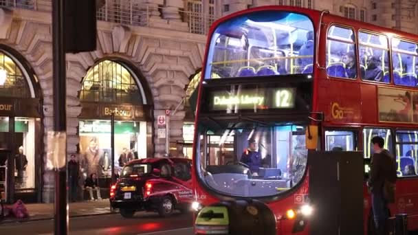 Autobús rojo de Londres esperando en Picadilly circo disparo nocturno - LONDRES, INGLATERRA — Vídeo de stock