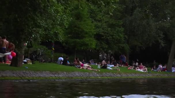 Människor avkopplande på stranden av Amsterdams kanaler — Stockvideo