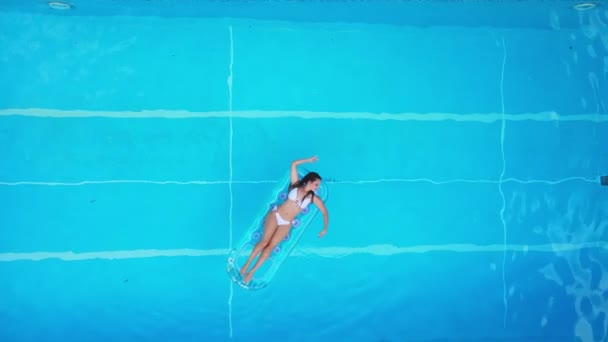 Csinos lány fekszik egy matracon a medencében. — Stock videók