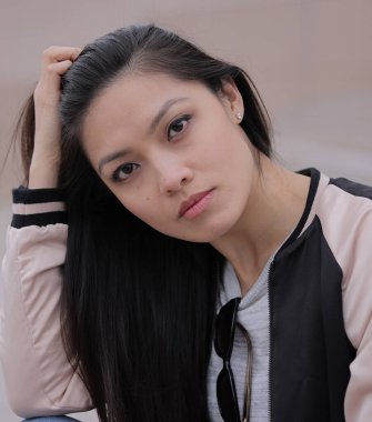 Genç Asyalı kadın kentsel alanda kameraya poz veriyor. İnsanlar fotoğraf çekiyor.