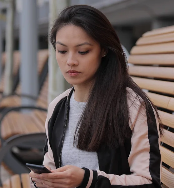 Young Asian woman writes text messages on her phone - people photography