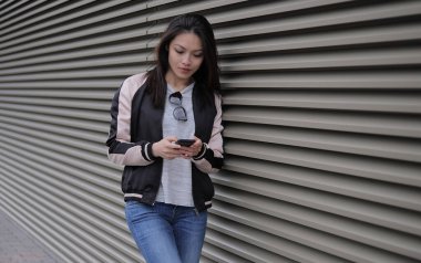 Genç Asyalı kadın telefonuna kısa mesajlar yazıyor. İnsanlar fotoğraf çekiyor.