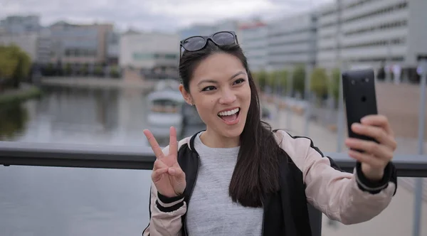 Joven asiática mujer toma un selfie en un área urbana — Foto de Stock