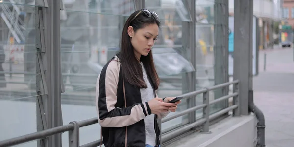 Giovane donna asiatica scrive messaggi di testo sul suo telefono — Foto Stock