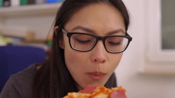 Young woman eats a pizza from delivery service while at work — Stock Video