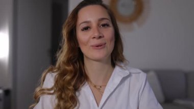 Video konferansındaki genç kadın kameraya konuşuyor.