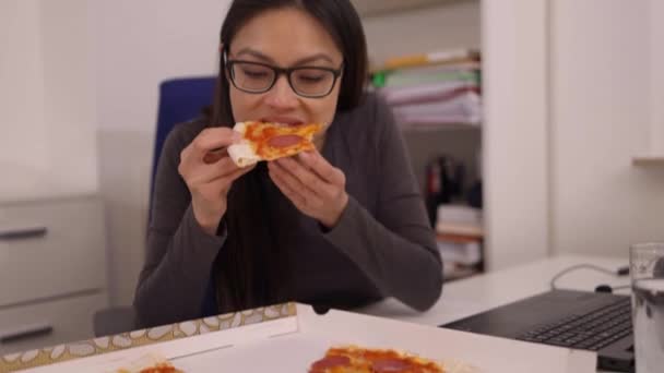 Genç bir kadın işteyken teslimat servisinden pizza yiyor. — Stok video