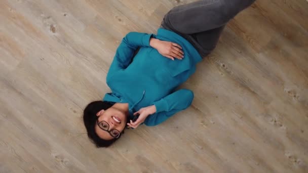 Mujer joven yace en el suelo y hace llamadas telefónicas — Vídeos de Stock