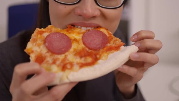 Young woman eats a pizza from delivery service while at work — Stock Video