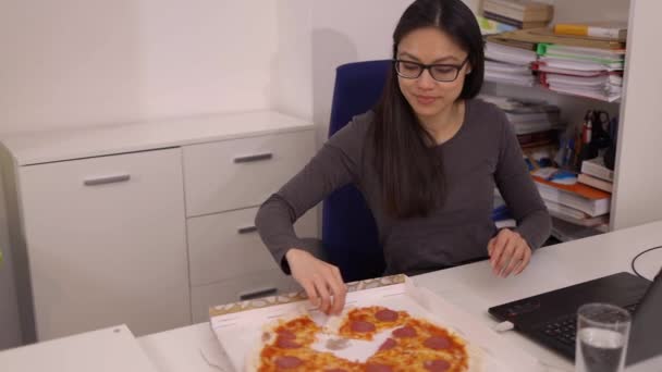 Giovane donna mangia una pizza dal servizio di consegna mentre al lavoro — Video Stock