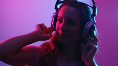 Genç bir kadın kulaklıkla müzik dinliyor, şık bir şekilde aydınlatılmış.