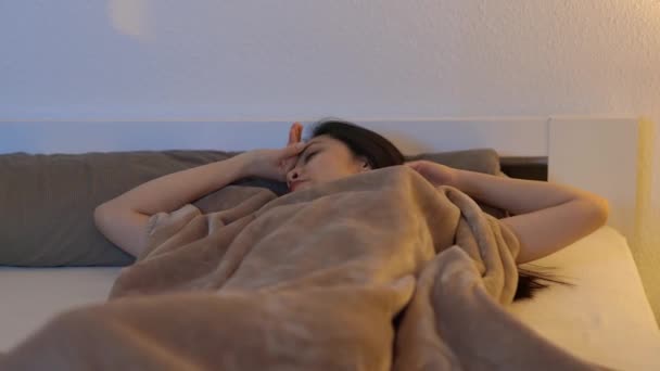 Joven asiática mujer despierta mientras ella se encuentra en la cama — Vídeo de stock