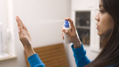 Genç Asyalı kadın Covid-19 sırasında ellerini dezenfekte ediyor. Yavaş çekim.