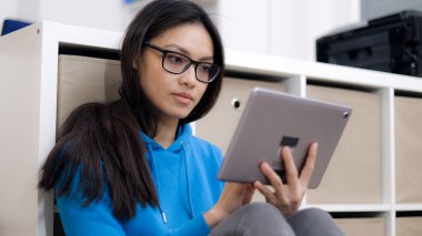 Genç bir kadın tablet bilgisayarla çalışıyor.