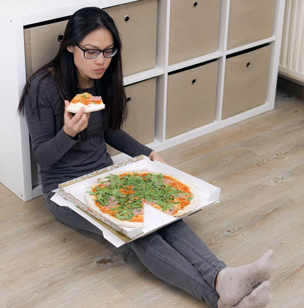 Young woman sits on the floor and eats pizza — Stock Photo, Image