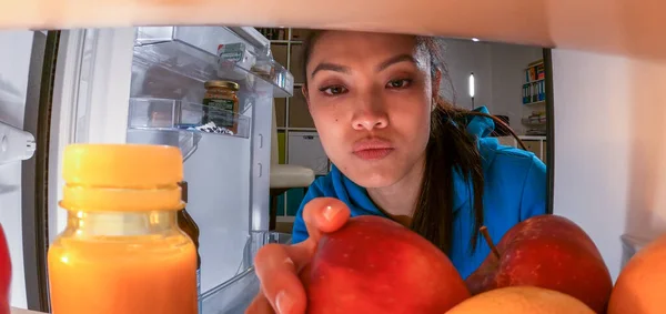 Young woman searches for food and drinks in the fridge — Stock Photo, Image