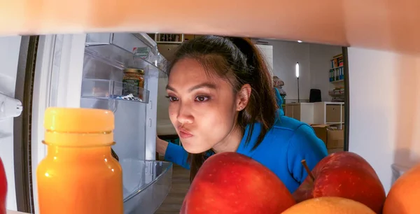 Young woman searches for food and drinks in the fridge — Stock Photo, Image