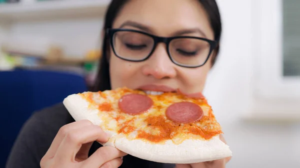 Młoda kobieta je pizzę z serwisu dostawczego podczas pracy — Zdjęcie stockowe