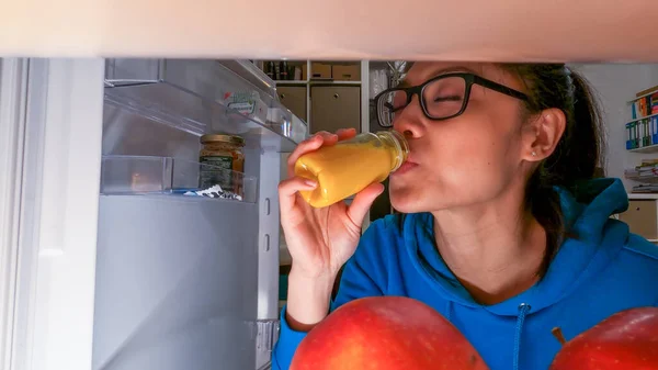 Young woman takes a delicious smoothie from her fridge — Stock Photo, Image