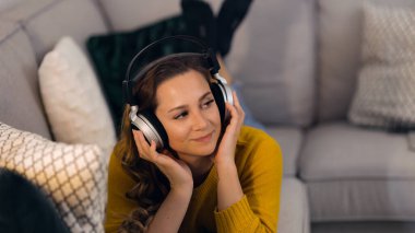 Güzel bir kadın dairesinde müzik dinler ve dinlenir.