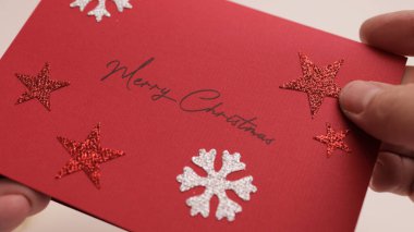 Elinde bir Noel tebrik kartı tutarken