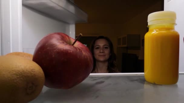 Mujer joven busca comida saludable en su refrigerador — Vídeo de stock