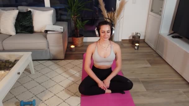 Young pretty woman relaxes while doing yoga in her apartment — Stock Video