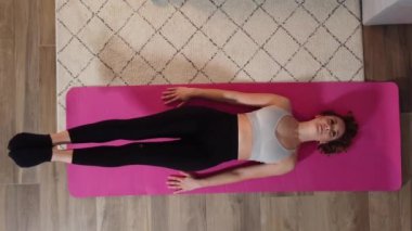 Genç ve güzel bir kadın evinde jimnastik yapıyor.