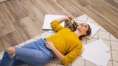 İşten yorgun düşmüş genç bir kadın yerde yatıyor.