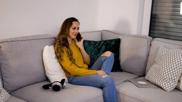 Jovem mulher relaxada no sofá no telefone — Fotografia de Stock