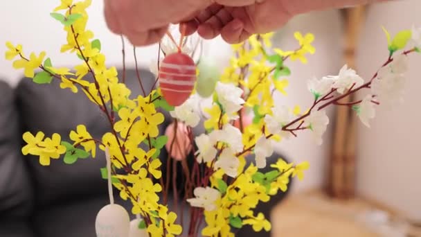 Einen Blumenstrauß mit bunten Ostereiern dekorieren — Stockvideo